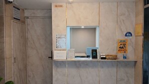 Un mostrador de recepción con detalles de mármol, una lámpara de techo y un extintor.