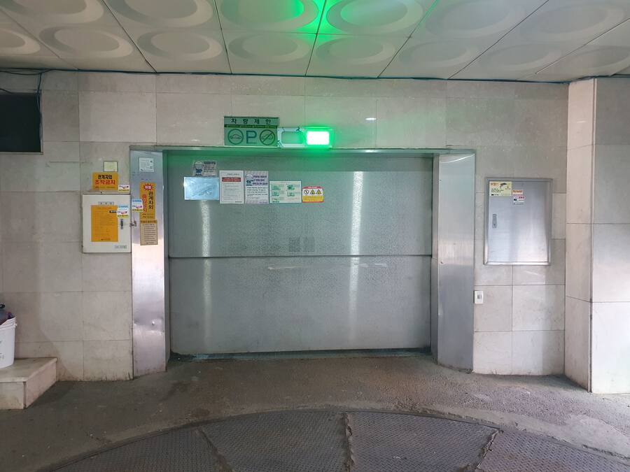 Ein Aufzug mit einem grünen Ausgangsschild, einer Metalttür und verschiedenen Hinweisen an der Wand.