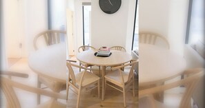 A round wooden dining table with six chairs, a clock on the wall, and a door leading to another room. - Charming 2BDR Apartment in Richmond close to MCG (Richmond)