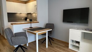 A compact living space with a kitchenette, a dining area with two chairs, a TV, and a white cabinet. - Haus Saturn Studio STUDIO by Interhome (Saas-Grund)