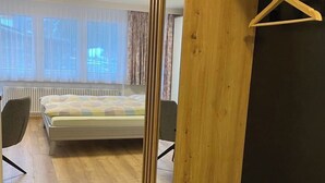 A bedroom with a wooden wardrobe, a bed, a chair, and a radiator. - Haus Saturn Studio STUDIO by Interhome (Saas-Grund)