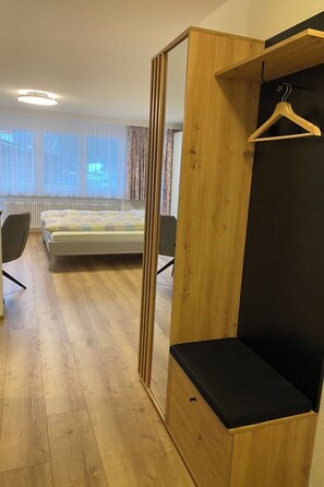 Ein Schlafzimmer mit Holzschrank, Bett, Sessel und Heizkörper.
