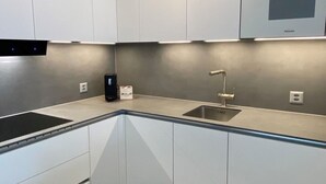 A modern kitchen with white cabinets, a stainless steel sink, and a built-in microwave. - Haus Saturn Studio STUDIO by Interhome (Saas-Grund)