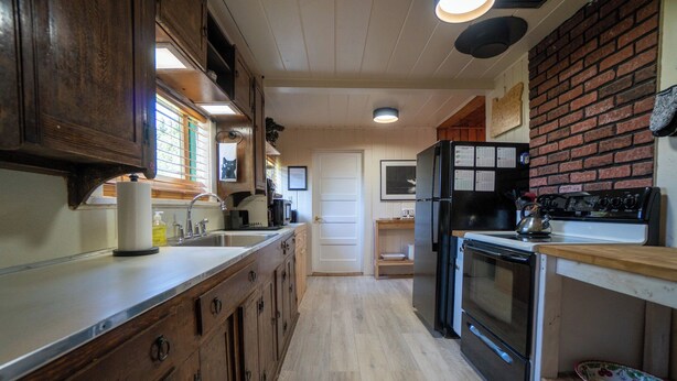 A kitchen with wooden cabinets, a refrigerator, an oven, and a sink.