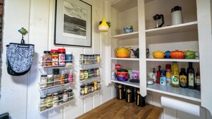 A kitchen with shelves stocked with spices, jars, and cooking utensils.