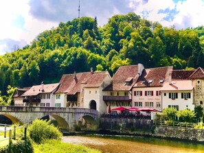 Ein Flussufer-Hotel mit traditioneller Architektur, einer Steinkonstruktion und üppiger Vegetation im Hintergrund.