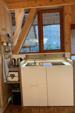 Una cocina compacta con un lavamanos empotrado, armarios de madera y ventana con vistas a un jardín.