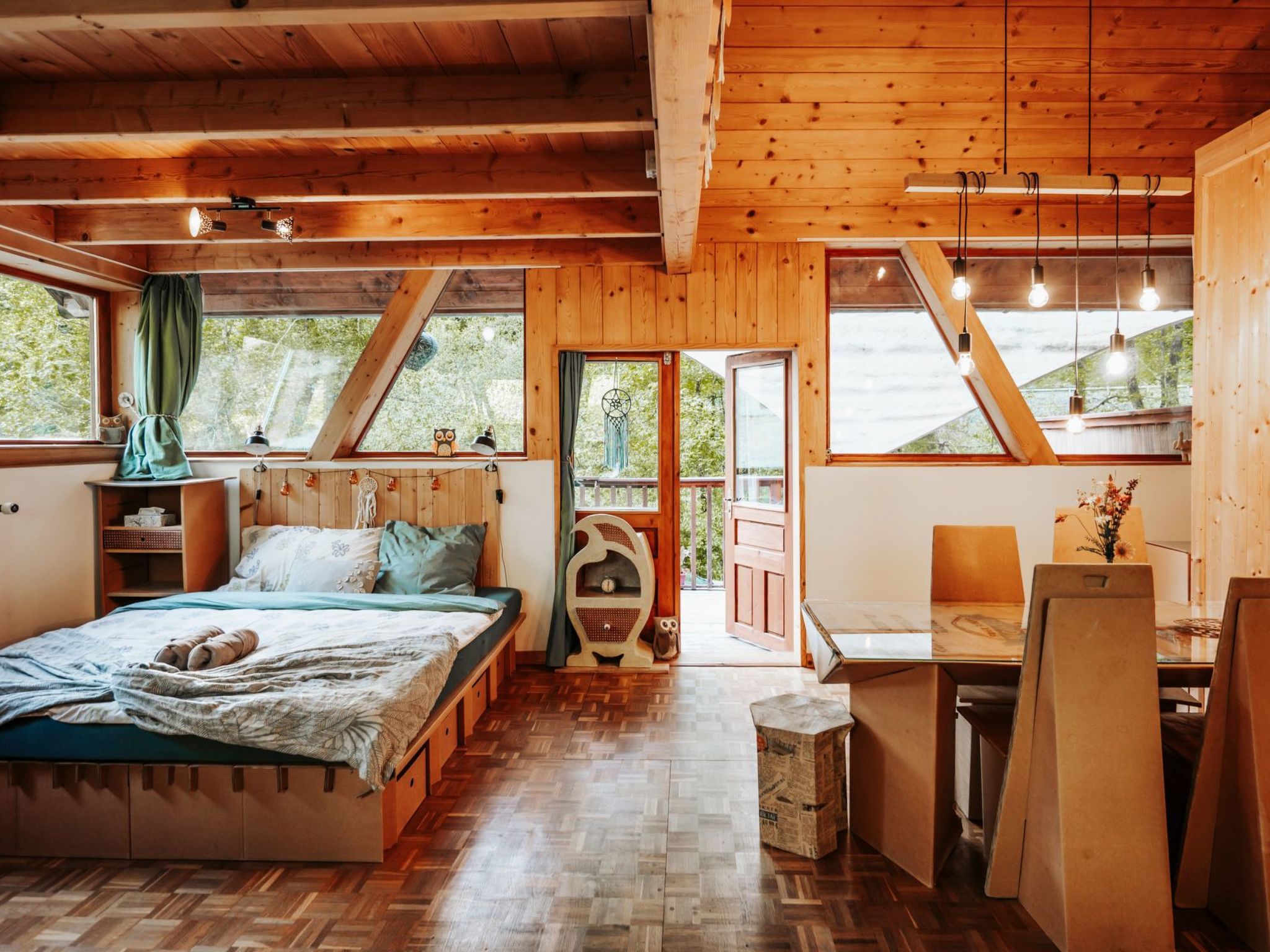 A cozy wooden cabin with a bed, a desk, and a view of the outdoors.