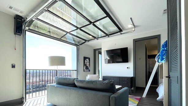 Ein modernes Wohnzimmer mit einer Couch, einem Fernseher und einem Balkon mit Blick.