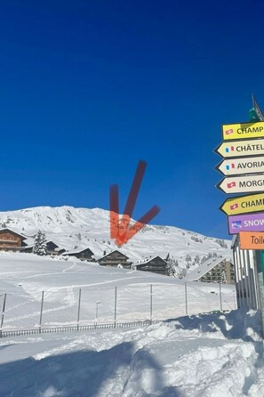 A snowy mountain landscape with a ski resort, including a signpost with multiple destination names. - Résid. les Rhodos, Le Yéti, (Les Crosets), by Interhome (Les Crosets)