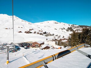 A ski resort with snow-covered slopes, wooden chalets, and a ski lift.