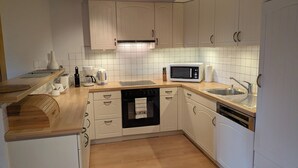 A modern kitchen with white cabinets, a microwave, a sink, and a wooden countertop. - Sundance 5, (Les Crosets), by Interhome (Les Crosets)