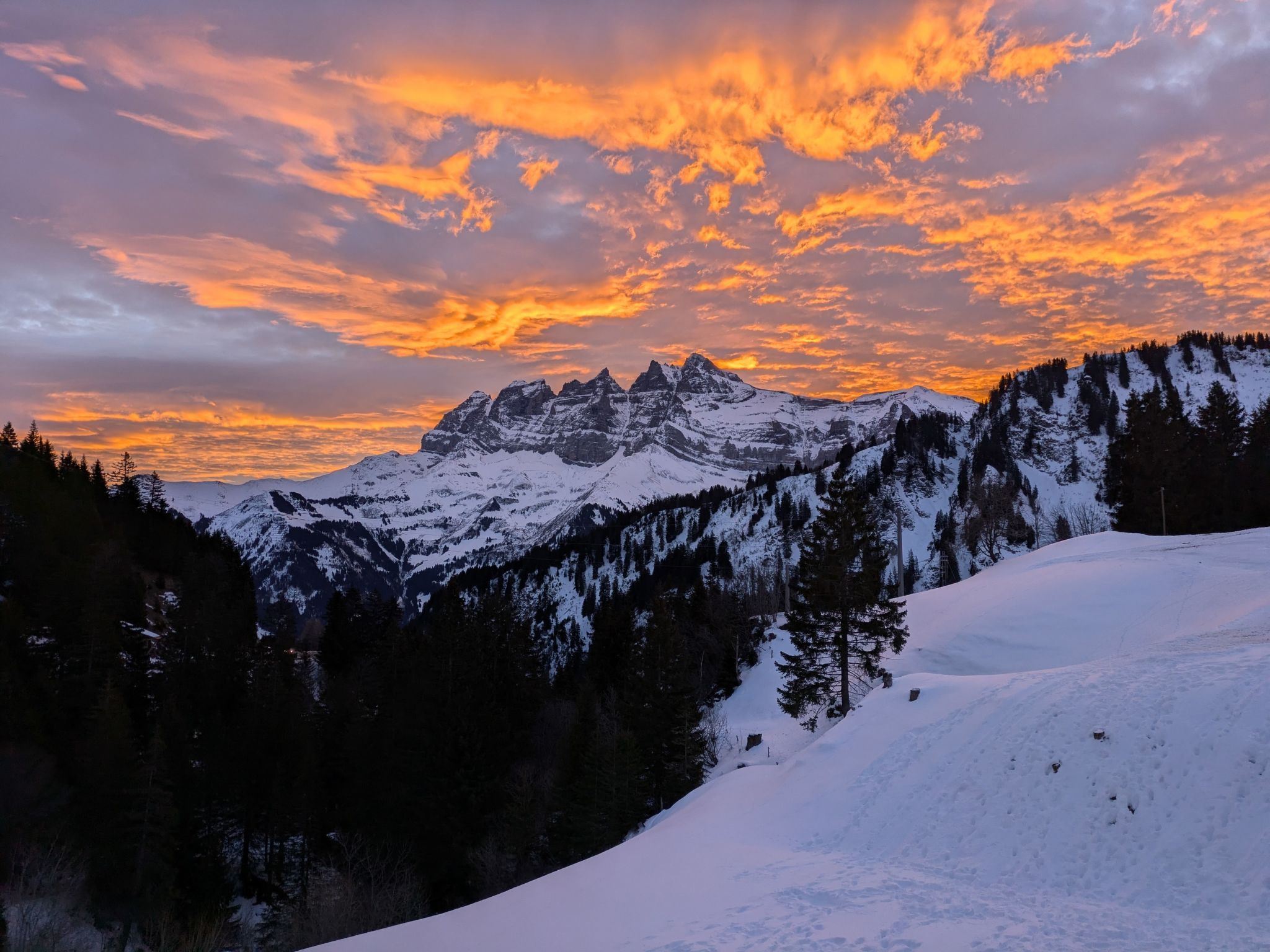 Une chaîne de montagnes enneigées, avec un ciel au coucher du soleil.