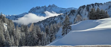 A snowy mountain landscape with a clear sky, a wooden structure in the foreground, and a snow-covered slope.