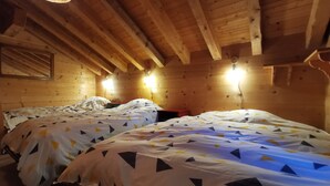 A wooden cabin room with two beds, a sloped ceiling, and wall-mounted lights. - Chalet Carmazin, (Morgins), by Interhome (Morgins)