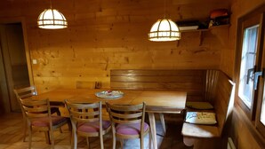 A wooden interior with a table, chairs, a bench, and pendant lights. - Chalet Carmazin, (Morgins), by Interhome (Morgins)