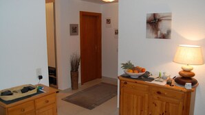 Ein Flur mit einem Holzschrank, einer Obstschale, einer Lampe und einer Tür.