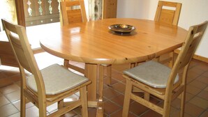 Ein runder Holztisch mit vier Stühlen, eine dekorative Schale auf dem Tisch und ein Fliesenboden.