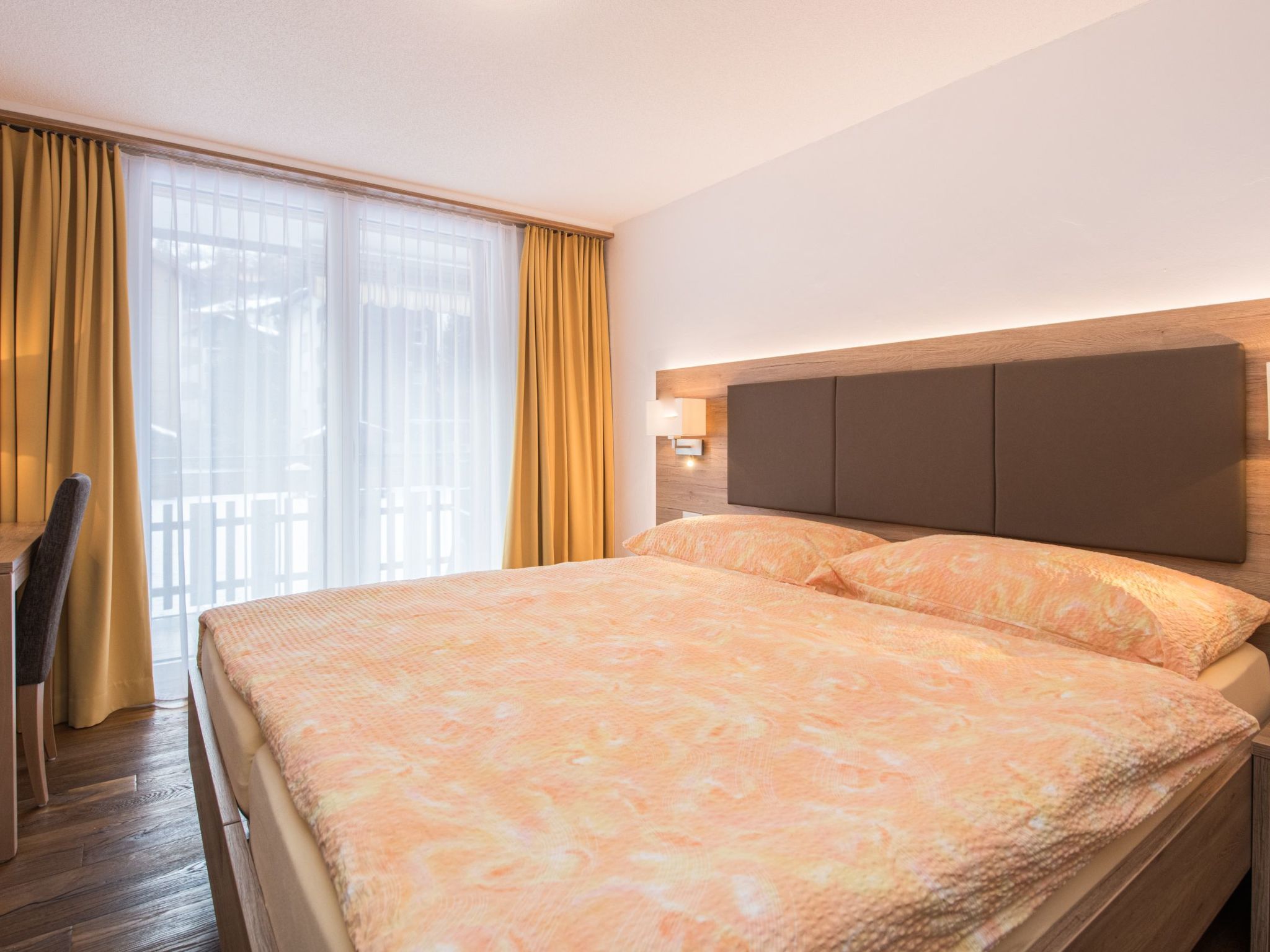 Une chambre d’hôtel avec un grand lit, un bureau et une vue sur l’extérieur par la fenêtre.