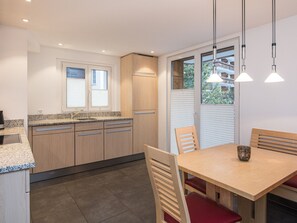 A modern kitchen with wooden cabinets, granite countertops, and a dining area with a wooden table and chairs. - Haus Matterhorngruss, (Zermatt), 1583.00 by Interhome (Zermatt)