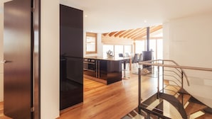 Una cocina moderna con piso de madera, un comedor y una escalera con barandillas de vidrio.