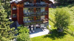Una baita di legno a più piani con balconi, immersa nel verde.