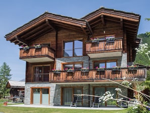 Ein mehrstöckiges Holzhaus mit Balkonen, Steinverzierungen und großen Fenstern.