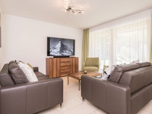 Uma sala de estar moderna com dois sofás de couro, uma mesa de centro de madeira e uma televisão em um armário de madeira.