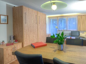 A modern living room with a wooden dining table, a sofa, and a potted plant. - Haus Felice, (Zermatt), 1333.00 by Interhome (Zermatt)