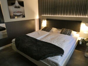 A hotel room with a bed, bedside lamps, a nightstand, and a mirror. - Haus Venus, (Zermatt), by Interhome (Zermatt)
