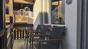A narrow outdoor corridor with wooden railings, a small table with chairs, and hanging spherical light fixtures. - Haus Venus, (Zermatt), by Interhome (Zermatt)