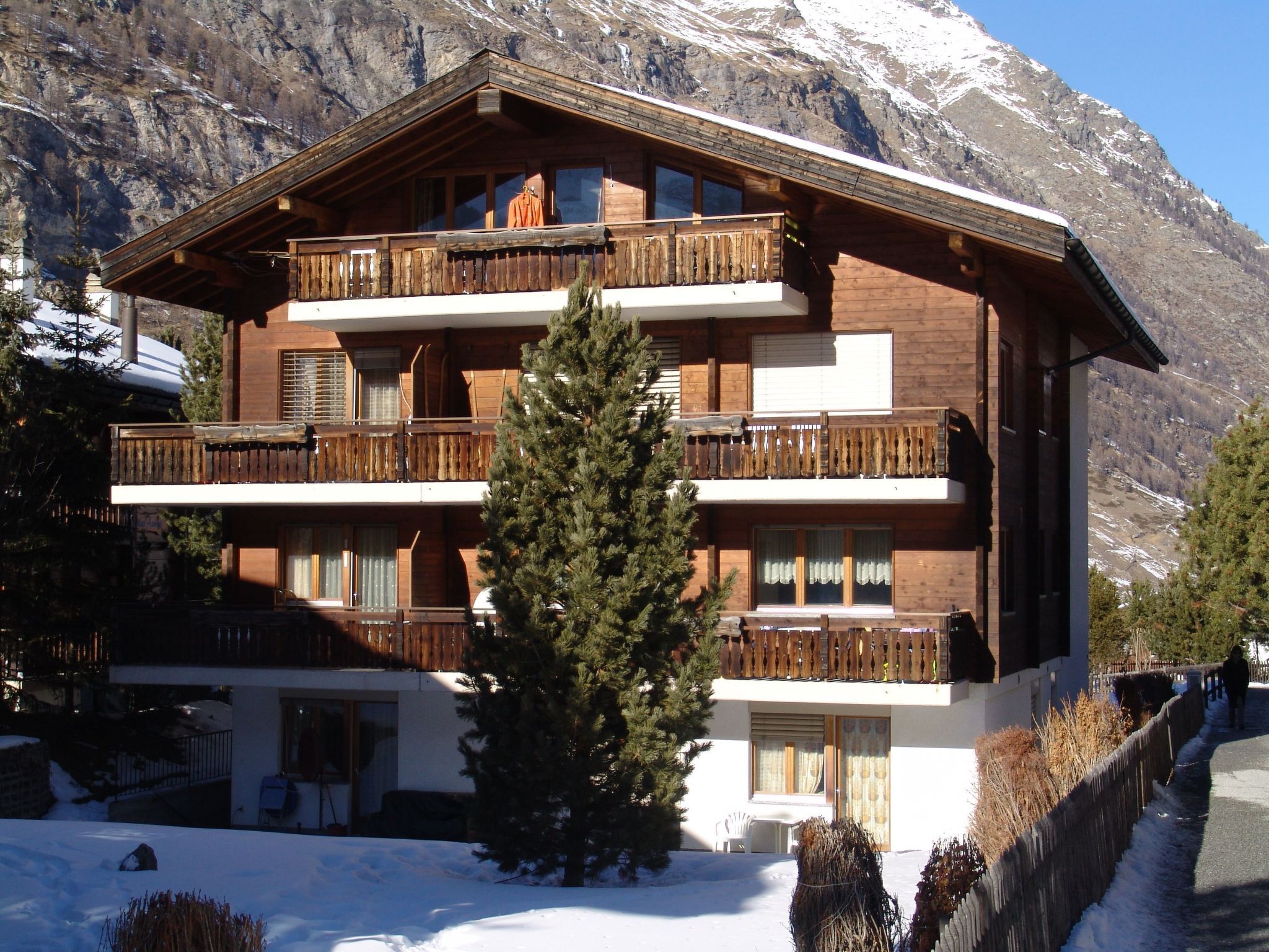 A multi-story wooden building with balconies, surrounded by snow and mountains.