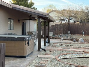 Eine Terrasse mit Whirlpool, Sitzgelegenheit und Ziergarten.