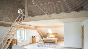 An attic bedroom with a loft bed, a wooden staircase, and a window. - Appartements - Ferme La Joux-Chaupe, (St-Ursanne), by Interhome (Saint-Ursanne)