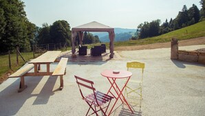 A gazebo with seating, a picnic table, and a small table with chairs. - Appartements - Ferme La Joux-Chaupe, (St-Ursanne), by Interhome (Saint-Ursanne)
