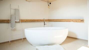Un baño moderno con una bañera independiente grande, un perchero y un techo con vigas de madera.