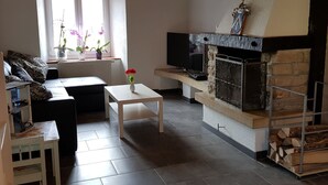 A living room with a sofa, a coffee table, a fireplace, and a television. - Appartement - Sous les Barres, (Montfaucon), by Interhome (Montfaucon)