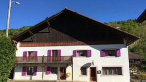 Edificio de dos pisos con balcón, techo de madera y paredes blancas.