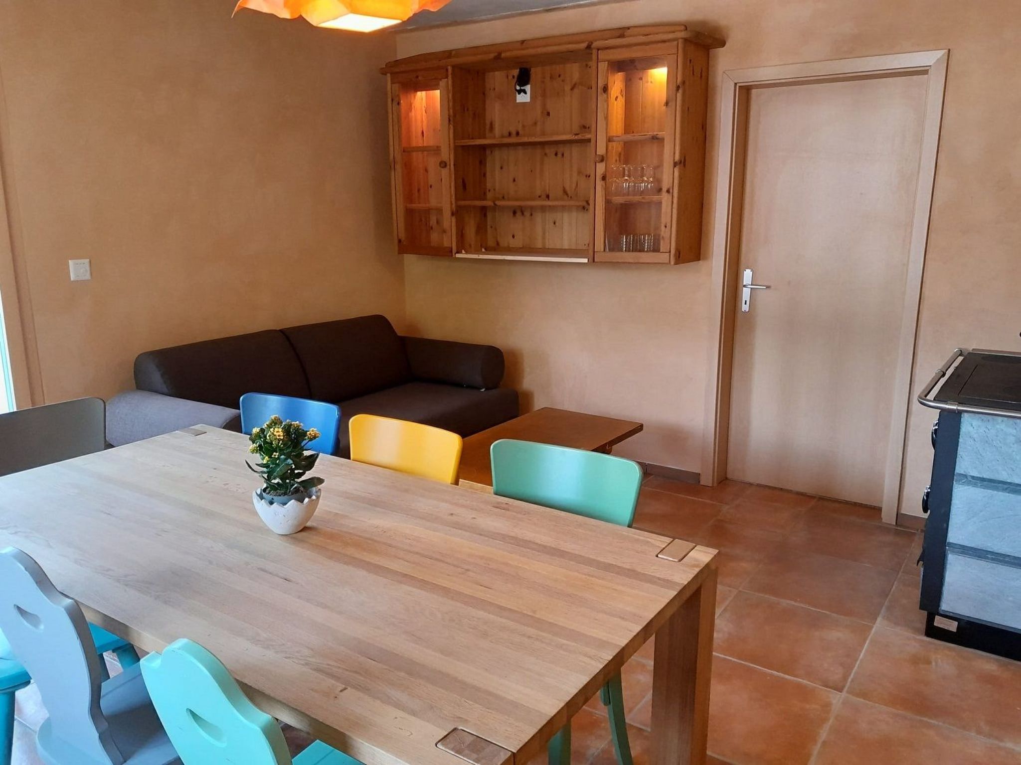 Un coin repas comprenant une table en bois, des chaises, un canapé et un meuble contenant de la verrerie.