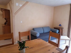 Ein Zimmer mit einem Holzespeisetisch, einem blauen Sofa und einem kleinen Holzschrank.