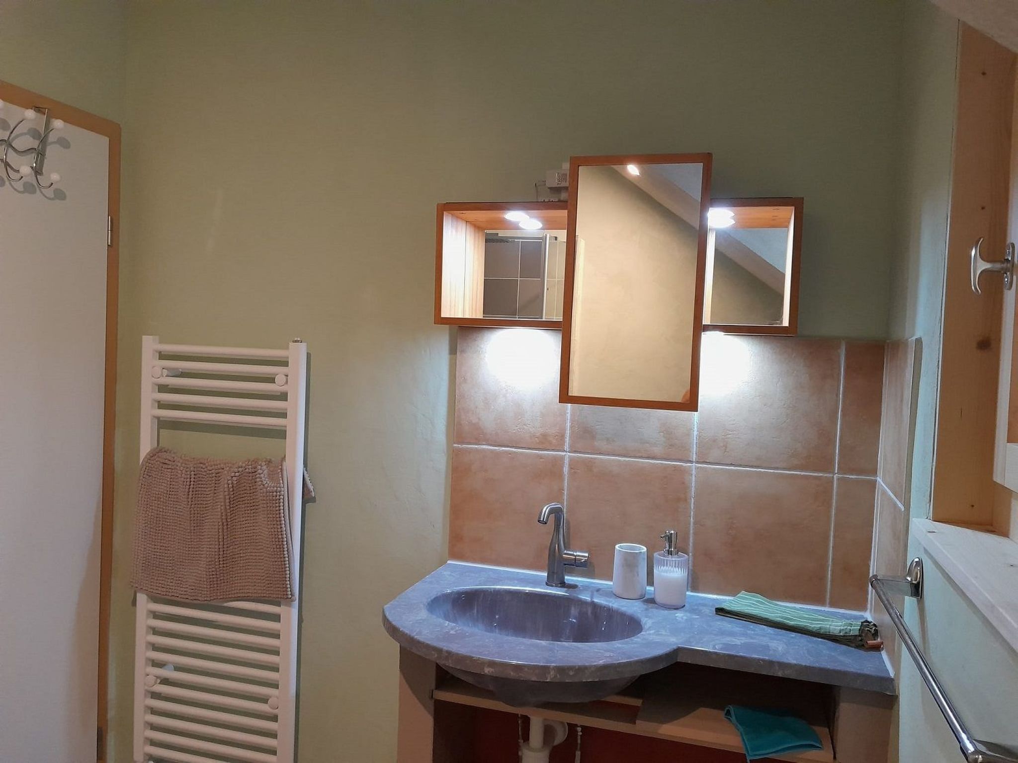 Ein Badezimmer mit Waschbecken, Spiegel, Handtuchhalter und Duschbereich.