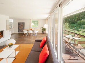 A modern living room with a sofa, dining table, and chairs. There is a balcony with outdoor seating. - Chalet Altesse, (Zermatt), 1054.01 by Interhome (Zermatt)