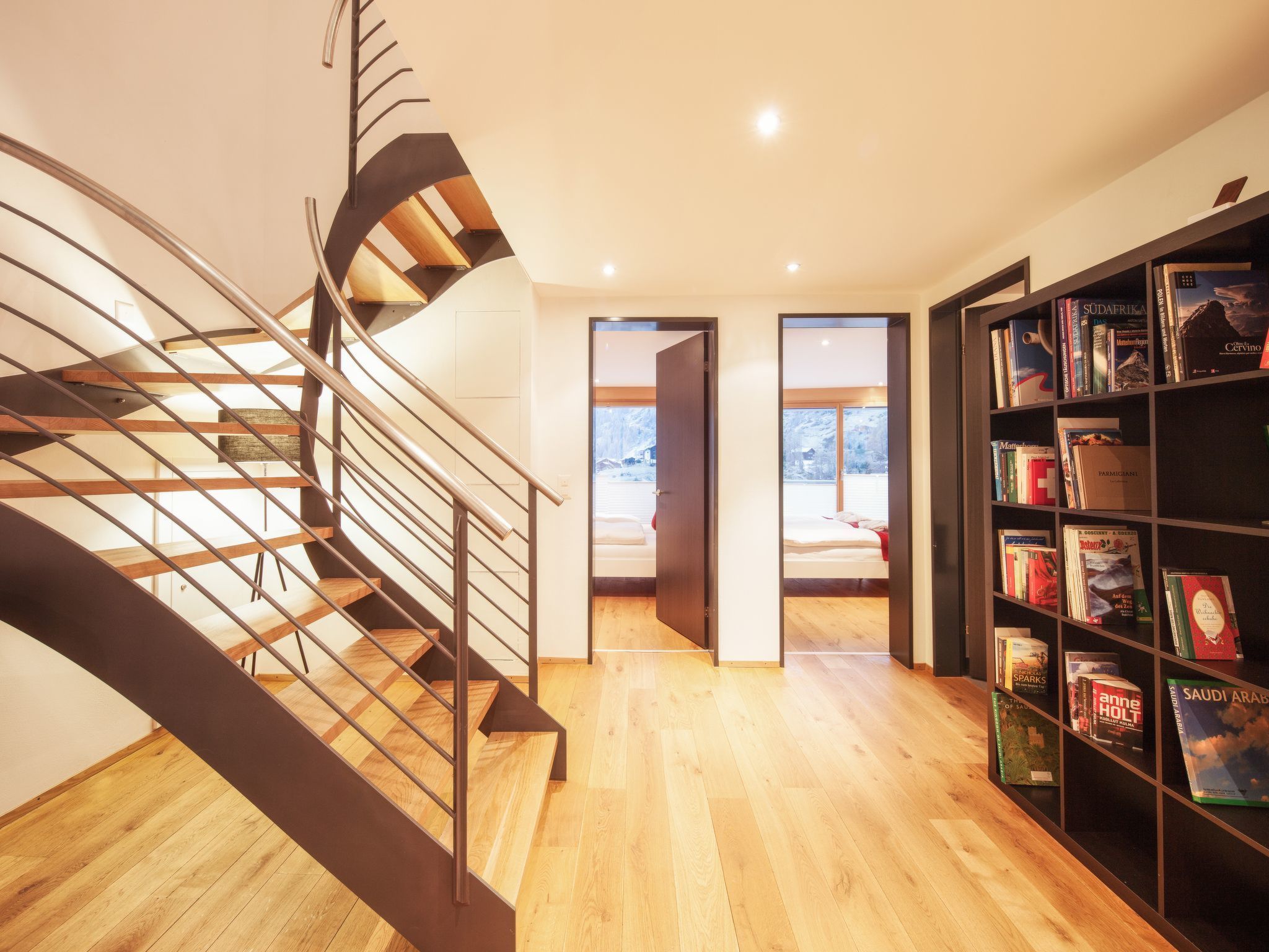 Un intérieur moderne avec un escalier en colimaçon, un plancher en bois et une bibliothèque remplie de livres.