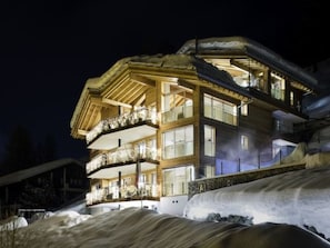 A multi-story hotel with balconies, large windows, and a snowy landscape. - Chalet Nepomuk, (Zermatt), 1632.00 by Interhome (Zermatt)