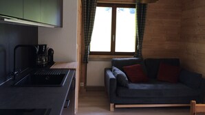 Eine kompakte Küche mit Einbauherd, Kaffeemaschine und einem Fenster mit Vorhängen.