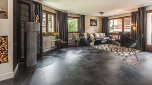 A modern living room with a fireplace, a sofa, a coffee table, and a dining area. - Haus Venus, (Zermatt), by Interhome (Zermatt)