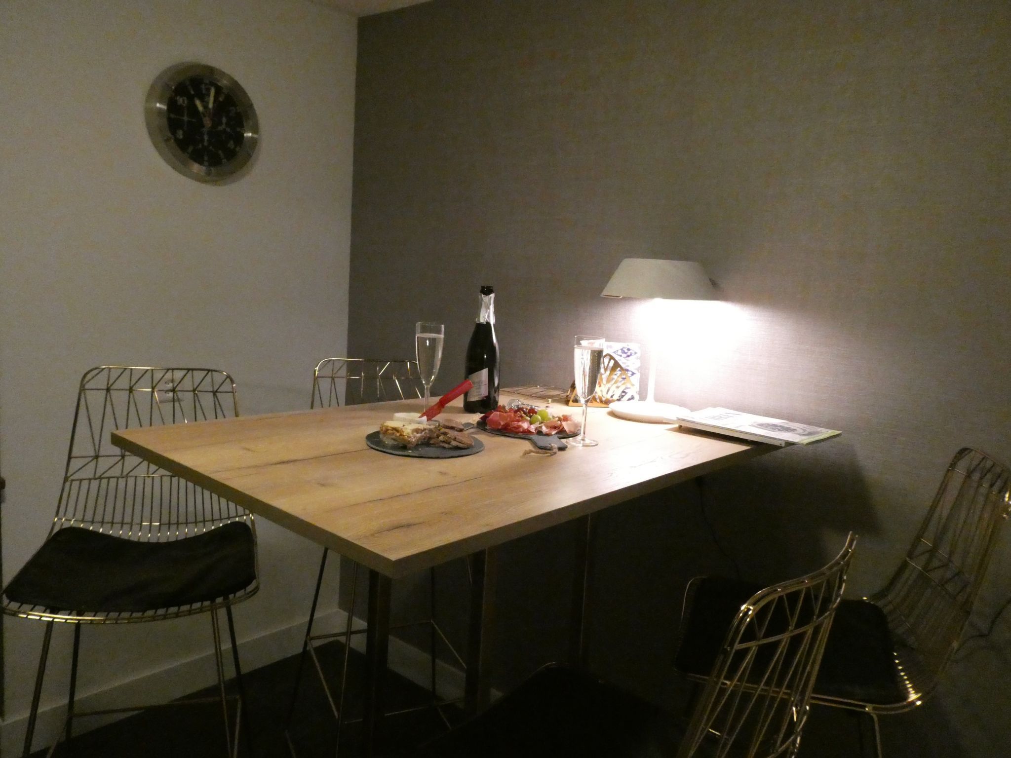 Et spisebord med stole, en flaske, glas og en lampe.