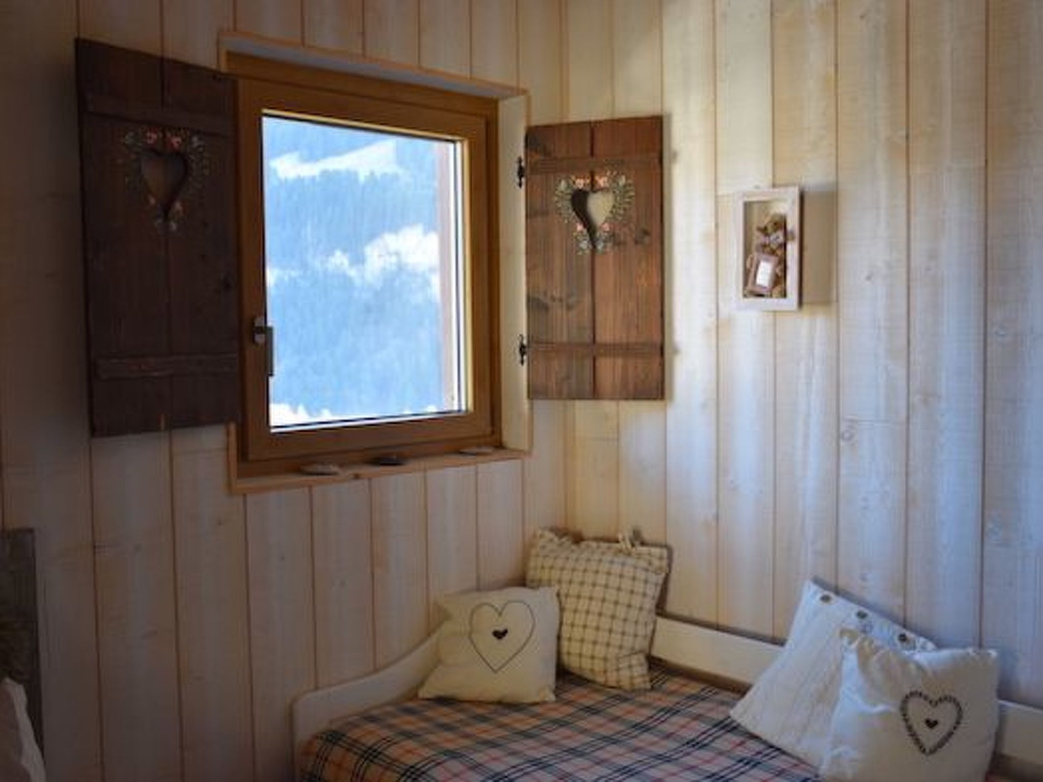 Una habitación acogedora con una cama, un ventanal y paredes de madera.
