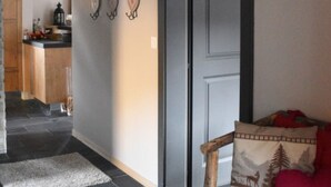 En hall med en träbänk, en dörr och ett uppstoppat rådjurshuvud som hänger på väggen.