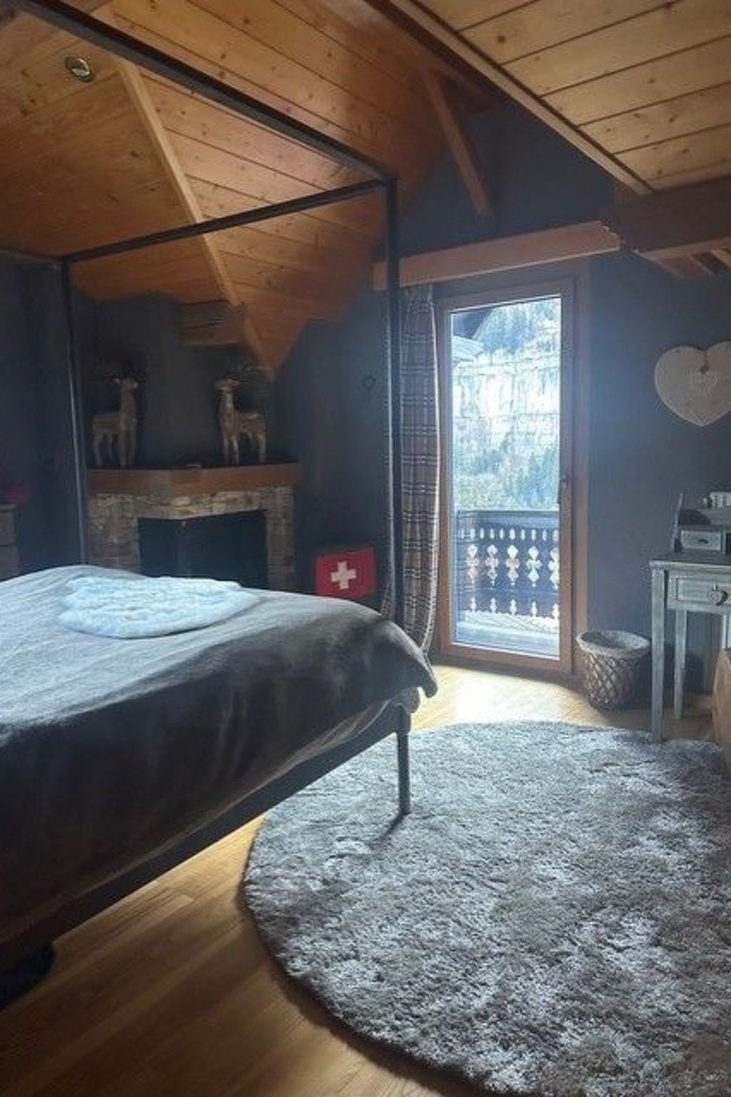 A bedroom with a bed, a fireplace, a window with a view, and a small table.